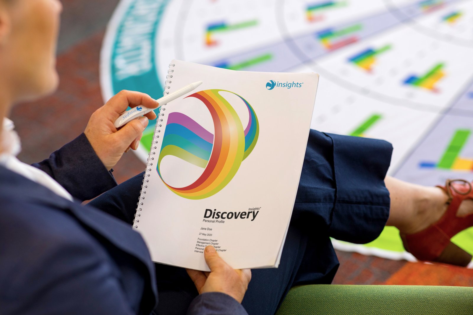 Teilnehmerin mit ihrem Insights-Discovery-Profil, im Hintergrund das große begehbare Insights-Rad auf dem Boden